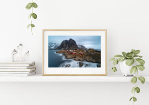 Smooth waves wash around rocks below a row of Lofoten fishing cabins