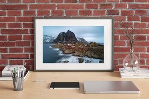 Snow traces mountain ridges behind Hamnøy’s red and white waterfront buildings