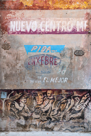Colour street detail of painted Havana signs, peeling plaster and layered graffiti.