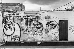 Black and white Havana street art with expressive eyes painted across peeling plaster.
