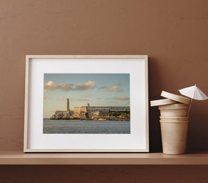 Colour coastal photograph of Havana’s Morro Castle and lighthouse in soft golden light.