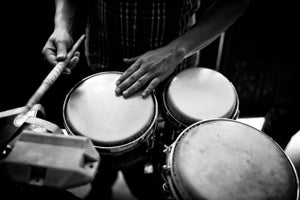 A musician holds a drumstick while resting one hand on a drumhead in Havana.