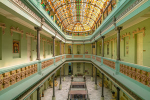 Colour architectural photograph of Hotel Raquel’s stained-glass ceiling above symmetrical green galleries.