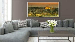 Golden sunset above clustered Istanbul buildings and a brightly lit mosque overlooking the water.