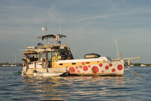 Weathered houseboat with a yellow stripe and red hull markings