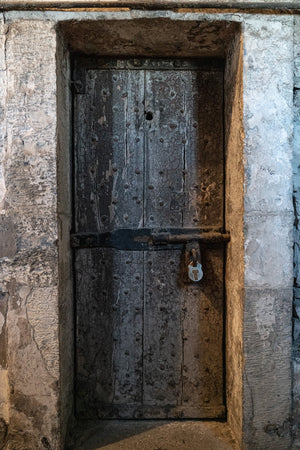 Old wooden prison door with cracked paint and iron fittings