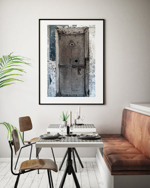 Old cell door with circular openings and peeling blue-white walls