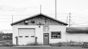 Monochrome photograph of a rural bait shop with garage door and minnows sign.