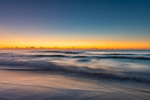 Long Reef Beach seascape with soft blue surf and a gold band of morning light
