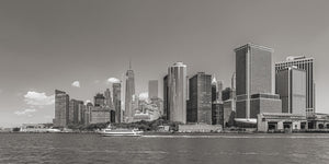 New York waterfront towers and a sightseeing boat beneath a lightly clouded sky
