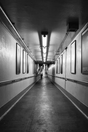 Man approaches along a station ramp beneath a row of fluorescent lights