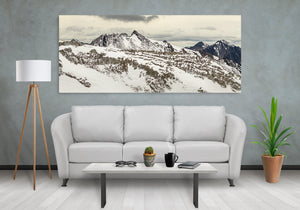 White snowfields surround jagged mountain summits beneath grey clouds