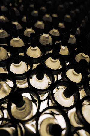 Rows of wine bottles glow softly within dark circular rack supports