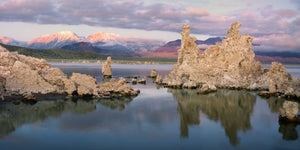 Pale limestone formations reflect in calm blue water at Mono Lake