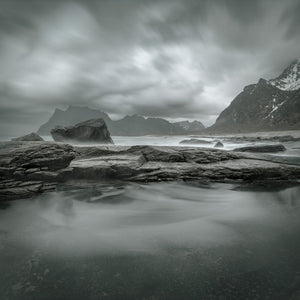 Layered coastal rocks and misty water at Kostbergan Beach in Norway