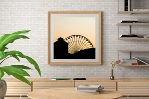 Dark silhouette of Navy Pier wheel spokes against a pale orange sky