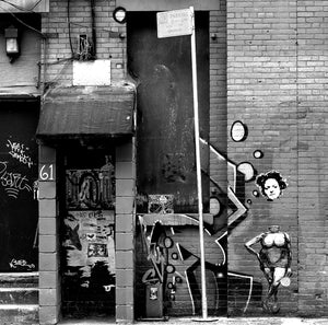 Graffiti-covered doorway and painted figures on a New York brick facade