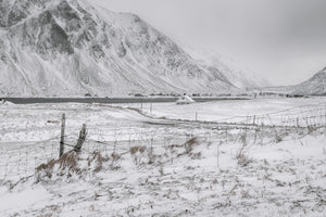 Snow-covered fields beside a Norwegian inlet and mountain slopes