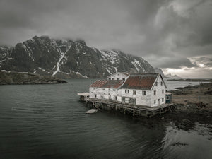 Weathered white timber hotel beneath snow-streaked Norwegian mountains