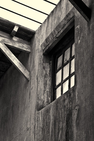 Tall multi-pane window set into cracked prison plaster