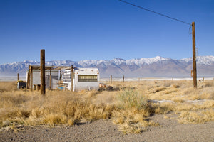 Weathered white trailer amid dry golden grass and utility poles