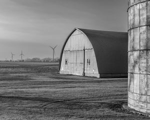 Black and white Ontario farm with a curved metal barn and silo