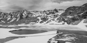 Black and white mountain lake with open water and snow near Ushuaia