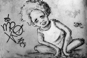 Street mural of a seated boy on cracked plaster in Havana