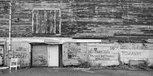 Peeling wooden siding, boarded upper window and handwritten towing warnings