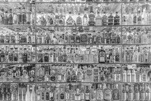 Miniature spirit bottles arranged on reflective glass shelves
