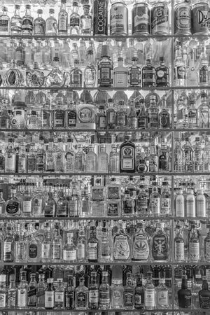 Tall display of spirits and beer cans on mirrored glass shelves