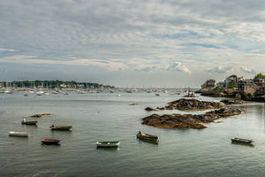 Dinghies floating on calm water with distant sailboats and coastal homes