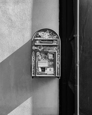 Sticker covered street mailbox with strong shadow Reykjavik Iceland