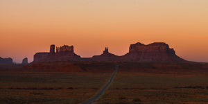 Monument Valley sandstone formations and a winding road at sunrise
