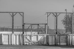 Black and white photograph of an outdoor rink gate beneath an open sky