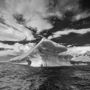 Overhanging iceberg with curved ridges above dark Antarctic water