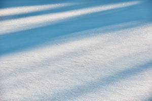 Sunlit snow crystals crossed by soft diagonal blue shadows