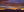 Sierra Mountains at sunset beneath layered purple clouds and a golden horizon.