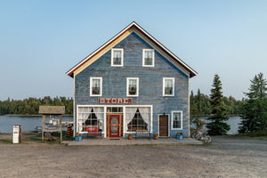 Weathered blue waterfront store with white windows and a red door