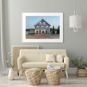 Historic general store beneath a pale blue sky beside evergreen trees