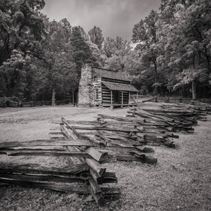 Rustic log cabin with a stone chimney surrounded by Smoky Mountains woodland