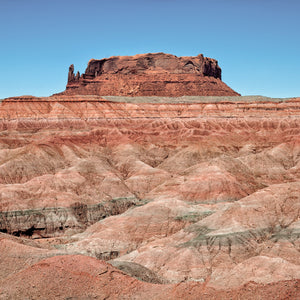 Red sandstone butte above pink and grey eroded desert ridges