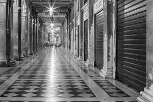 Illuminated corridor beneath the arcades of St Marks Square in Venice.