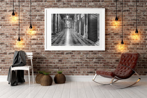 Hanging lamps cast reflections along a patterned Venetian arcade floor.