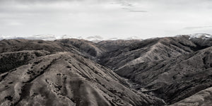 Rounded mountain slopes descend into a deep valley beneath a pale sky.