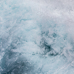 Close-up of turbulent blue water filled with froth and splashing sea foam.