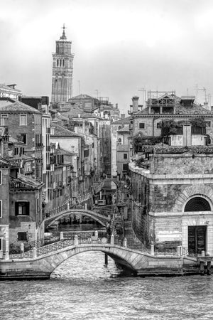 A narrow Venetian canal recedes beneath several arched footbridges