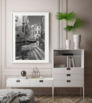 Monochromer Kanal von Venedig mit einer Gondel neben Steinstufen und alten Backsteinmauern