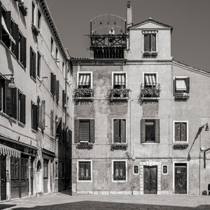 Sunlit Venetian facades with striped awnings, dark shutters and a rooftop terrace