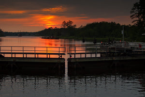 Sunset reflected on calm water behind dark lock gates.